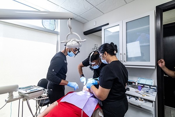 Multiple dentists performing dental work on a patient.