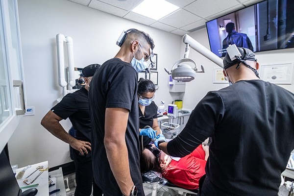 Multiple dentists performing dental work on a patient.