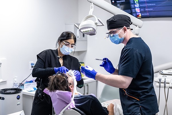 Multiple dentists performing dental work on a patient.