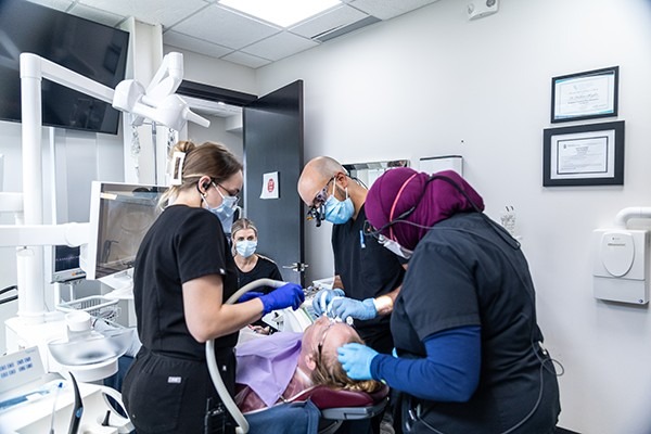Multiple dentists performing dental work on a patient.