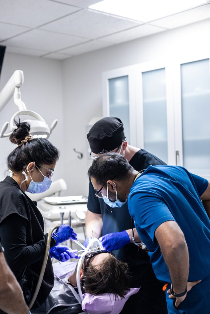 Multiple dentists performing dental work on a patient.
