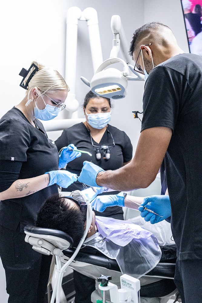 Multiple dentists performing dental work on a patient.