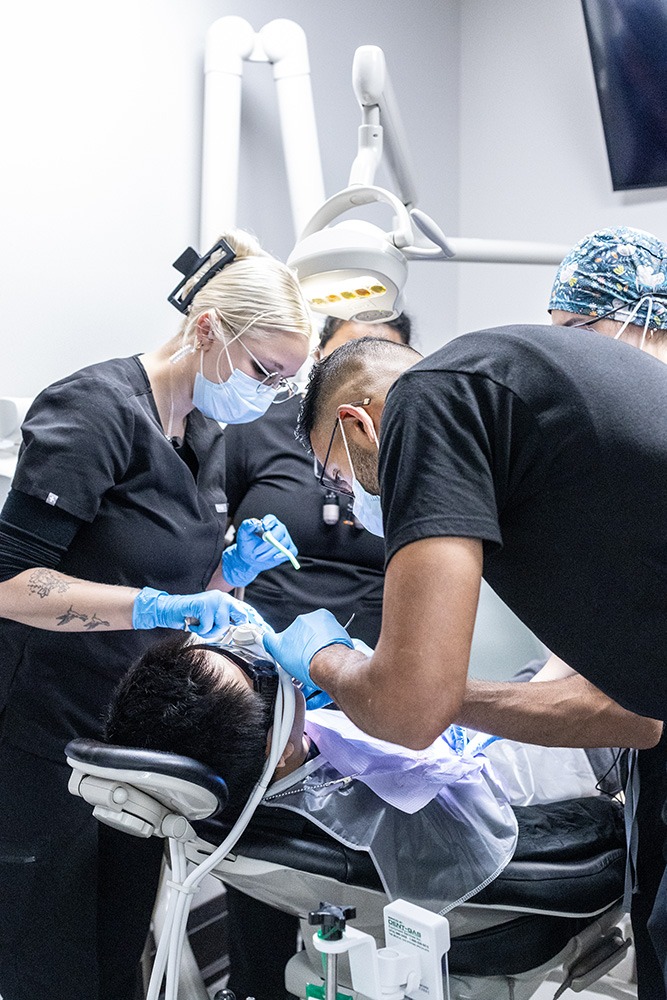 Multiple dentists performing dental work on a patient.