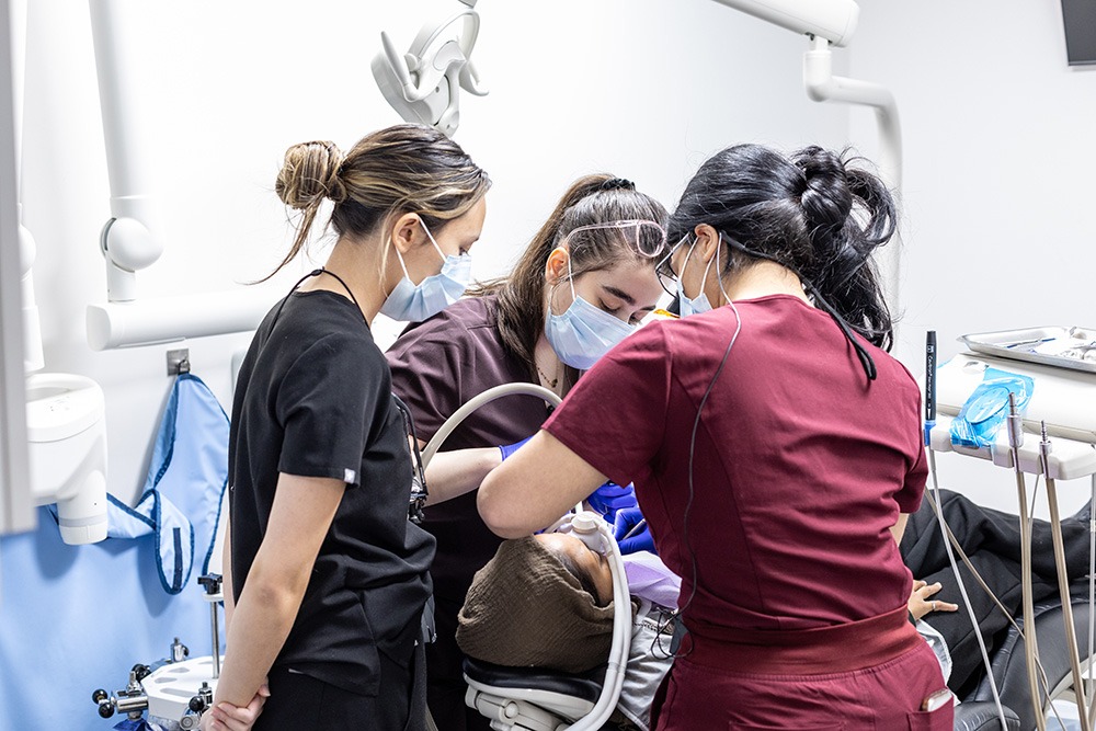 Multiple dentists performing dental work on a patient.