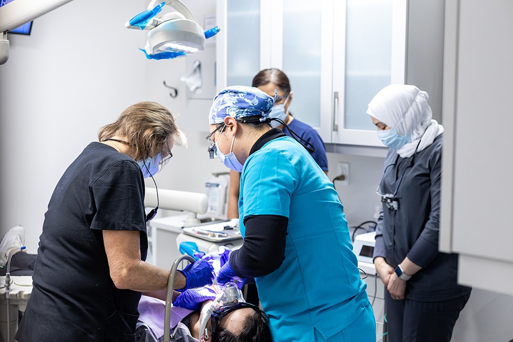 Multiple dentists performing dental work on a patient.
