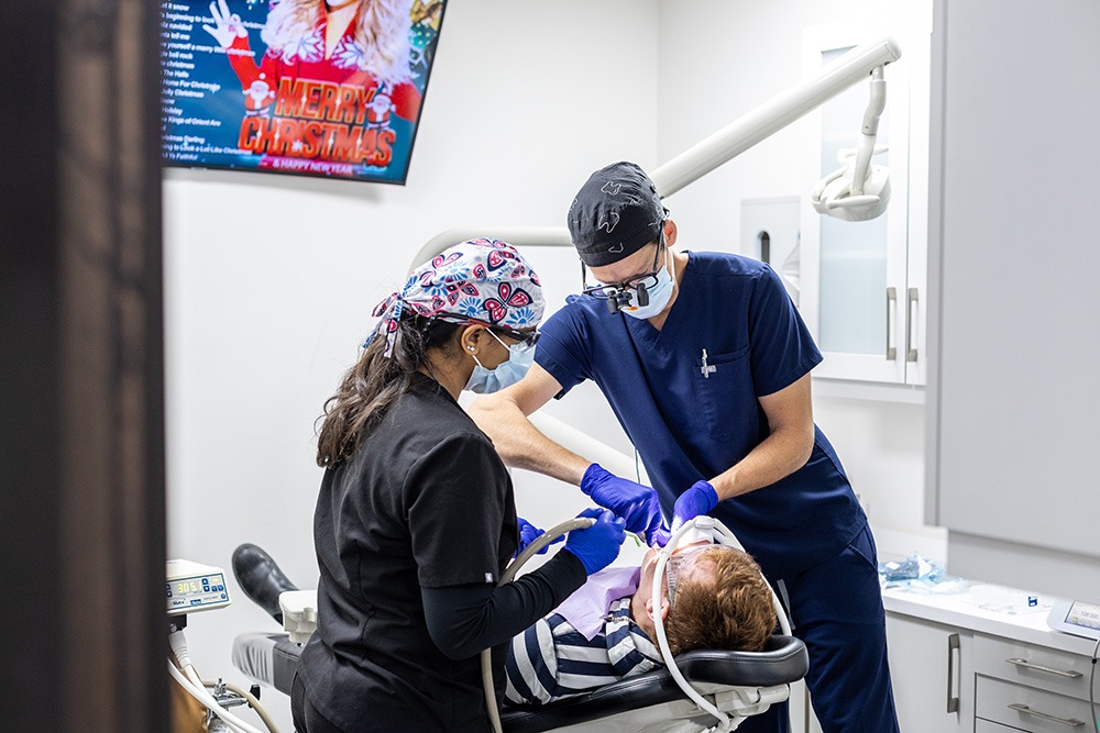 Multiple dentists performing dental work on a patient.