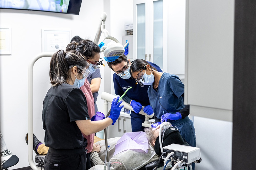 Multiple dentists performing dental work on a patient.